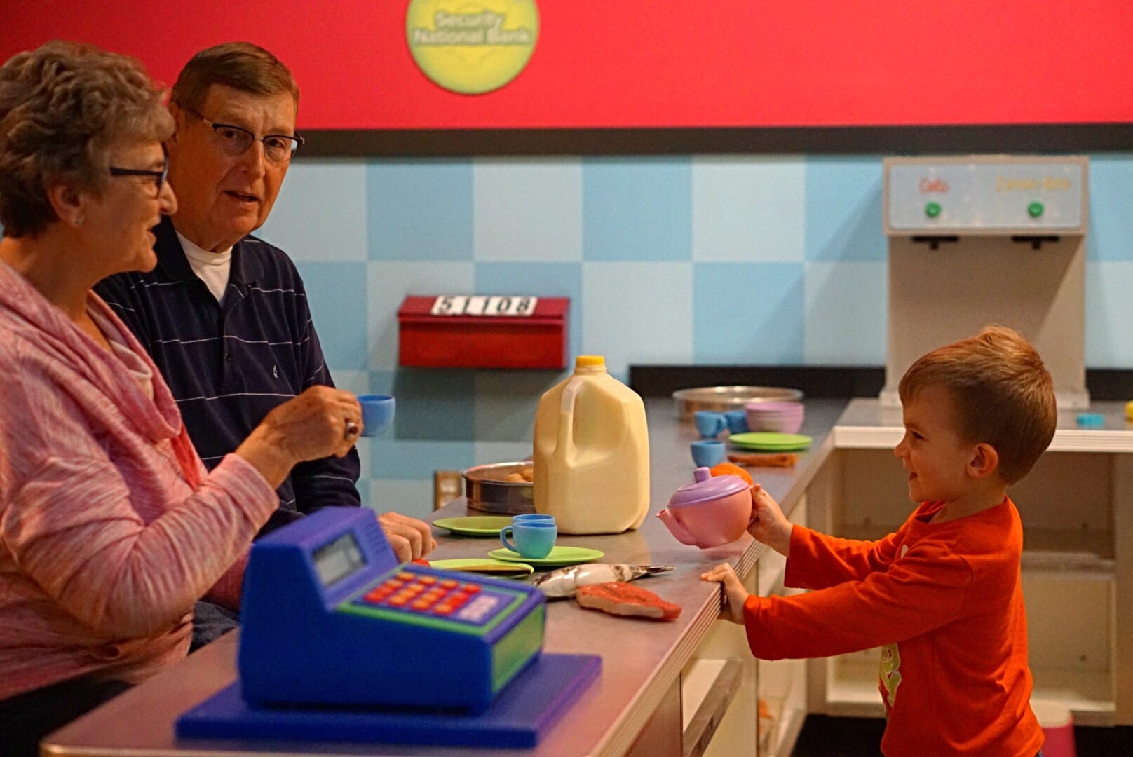 Child serving grandparents in the cafe exhibit.