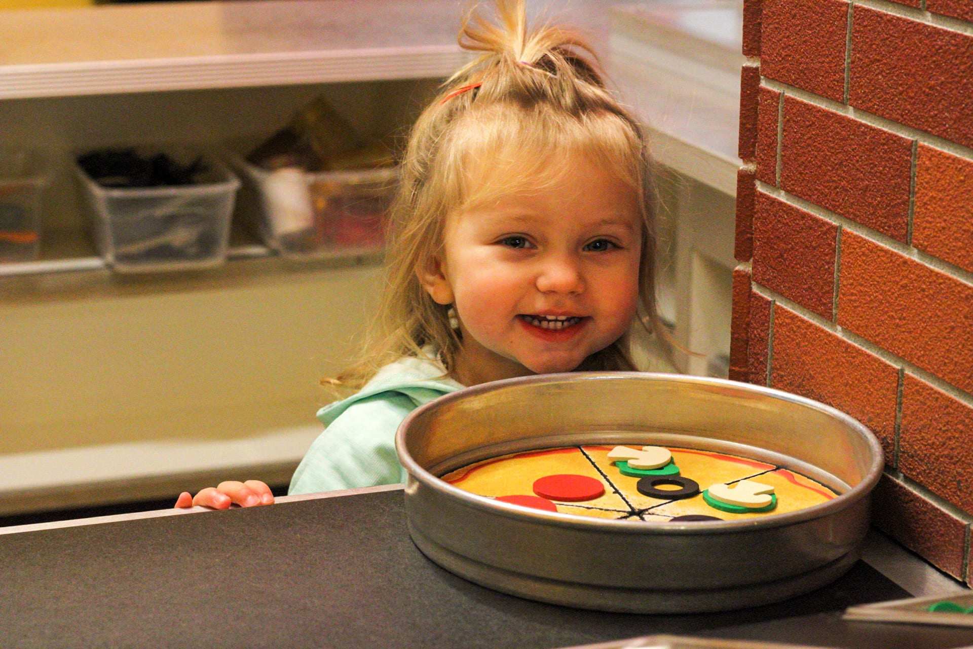 Child making pizza in the cafe exhibit.