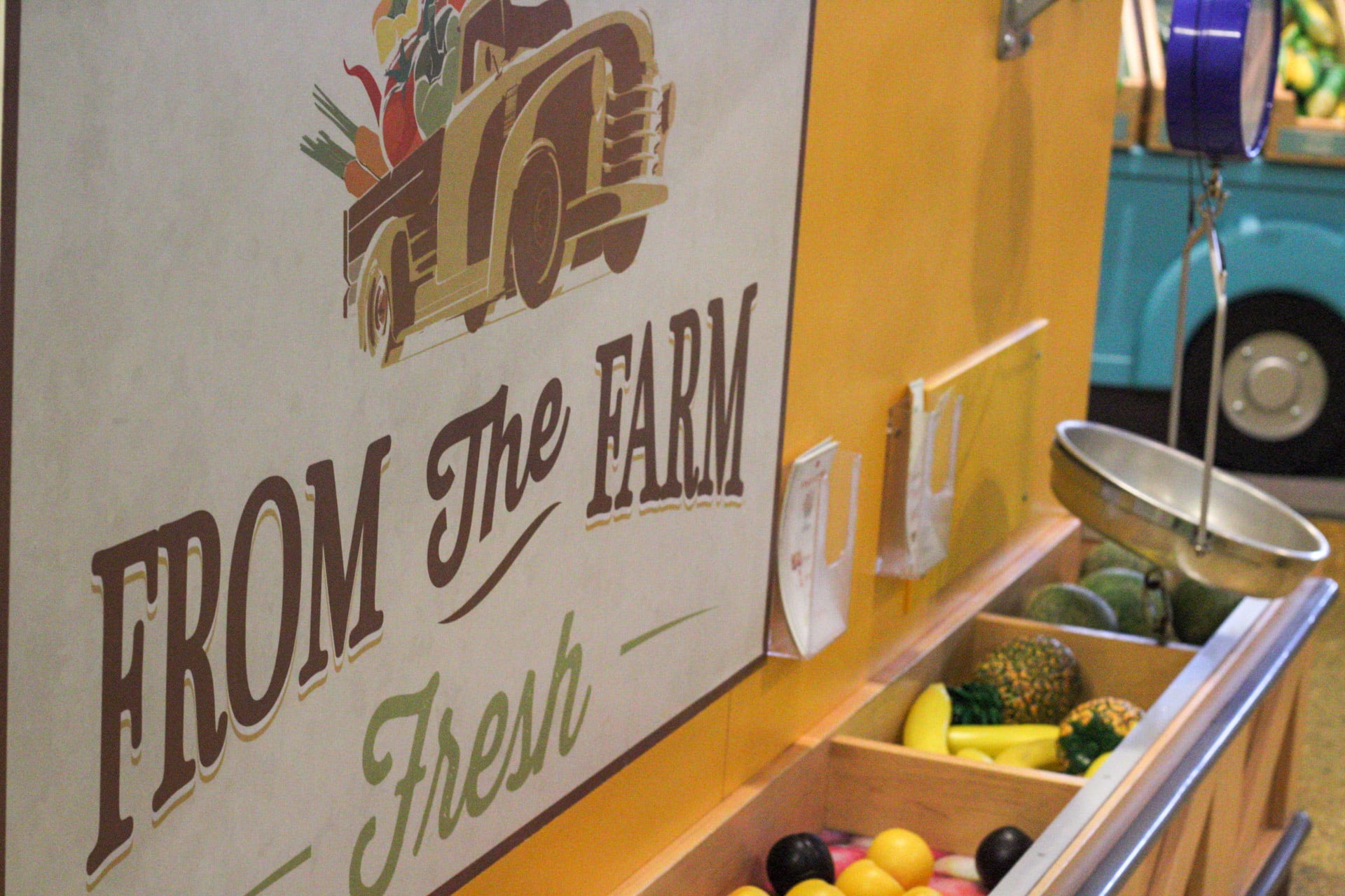 Fresh produce sign above the fruit stalls in the market exhibit.